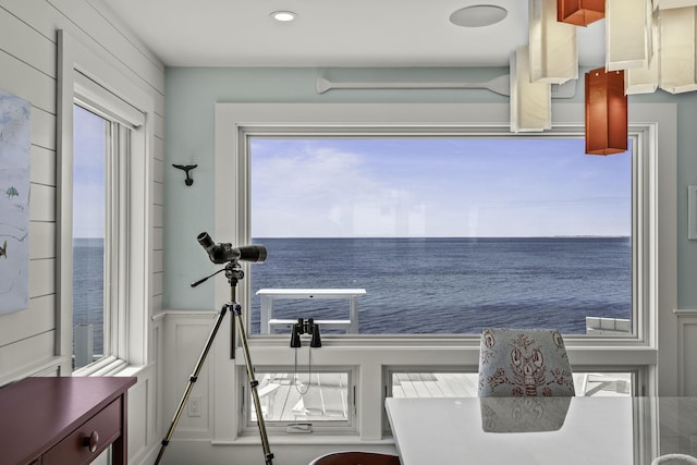 interior space with recessed lighting, wainscoting, a water view, and a decorative wall