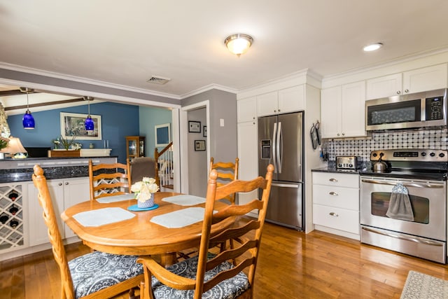 480 Forest Rd, South Yarmouth, MA 02664 - kitchen with stainless steel appliances, light wood-type flooring, crown molding, white cabinets, and decorative backsplash