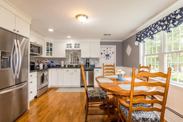 480 Forest Rd, South Yarmouth, MA 02664 - kitchen featuring appliances with stainless steel finishes, dark countertops, ornamental molding, light wood finished floors, and decorative backsplash