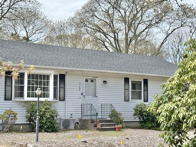 view of front of property featuring a cooling unit and a shingled roof