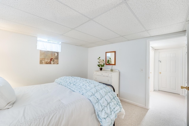 bedroom featuring baseboards, a paneled ceiling, and light colored carpet