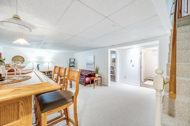 dining area with bar area, carpet flooring, stairs, and a paneled ceiling