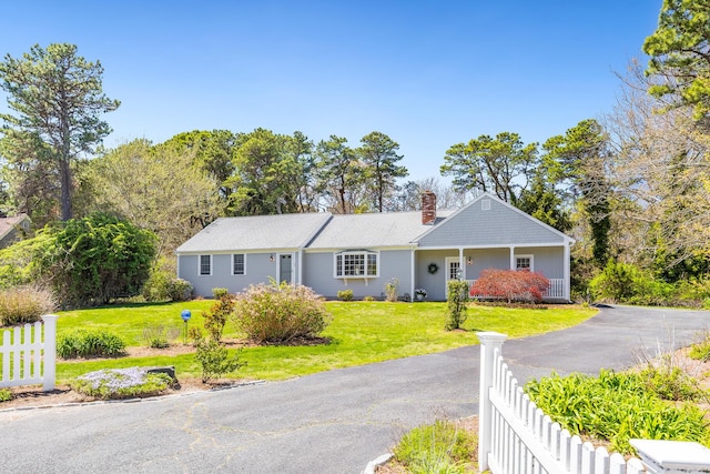 ranch-style home with a front lawn, fence, driveway, and a chimney