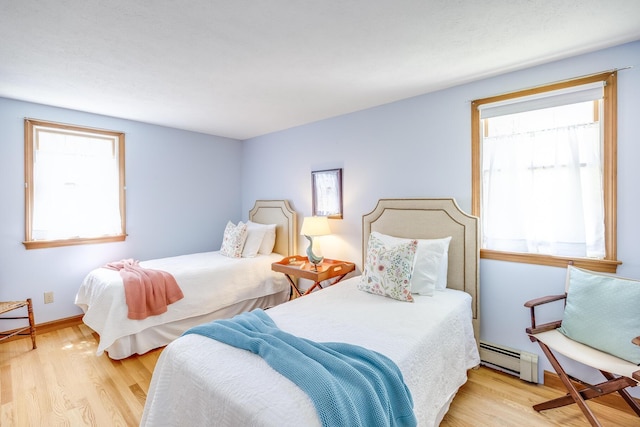bedroom with a baseboard radiator and wood finished floors