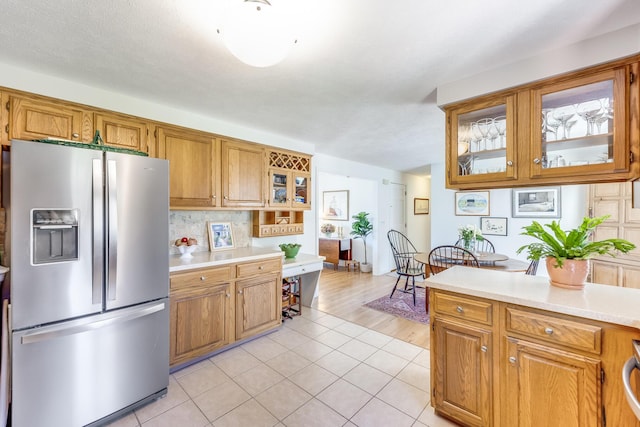 kitchen featuring light countertops, brown cabinets, and stainless steel refrigerator with ice dispenser
