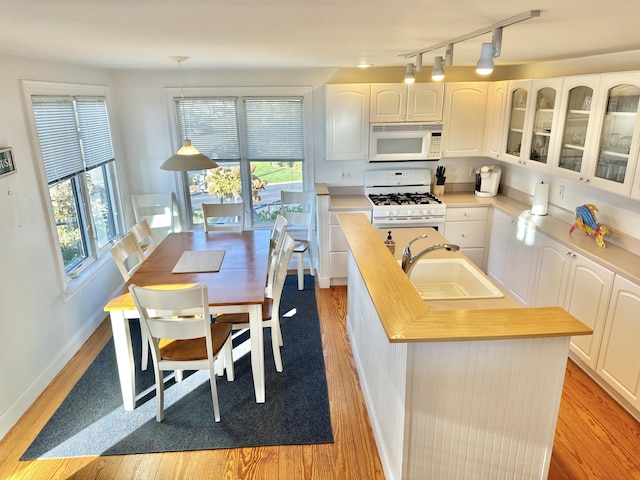 kitchen with sink, decorative light fixtures, white cabinetry, and white appliances