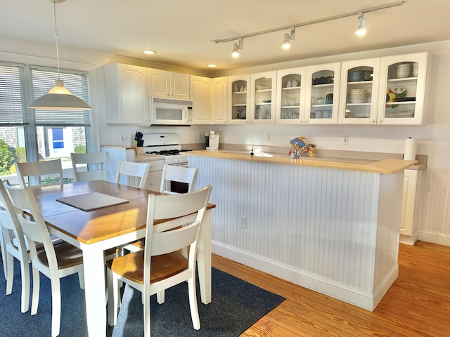 kitchen with light hardwood / wood-style floors, white cabinetry, white appliances, and pendant lighting