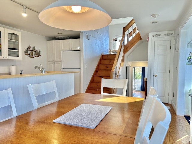 dining space with light hardwood / wood-style floors and track lighting