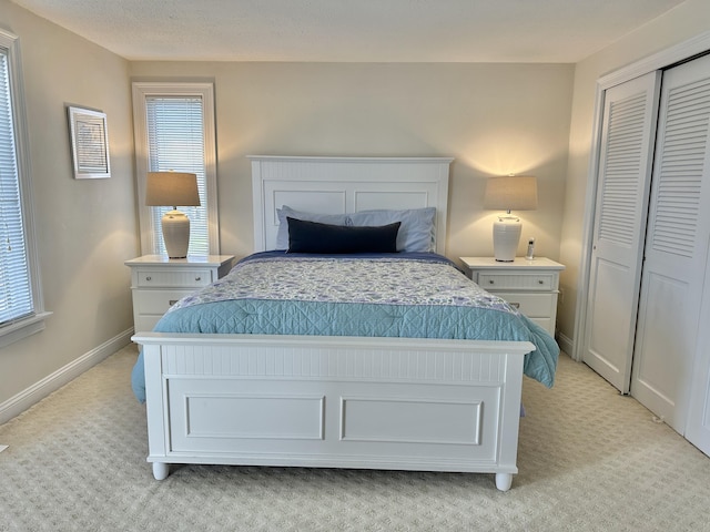 bedroom with multiple windows, light colored carpet, and a closet