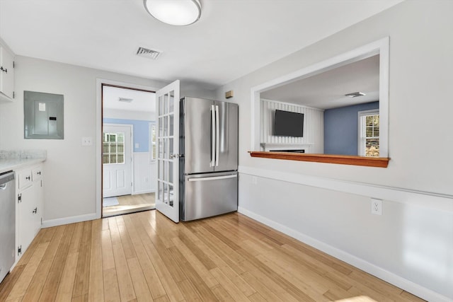 kitchen featuring white cabinetry, appliances with stainless steel finishes, electric panel, and light hardwood / wood-style floors