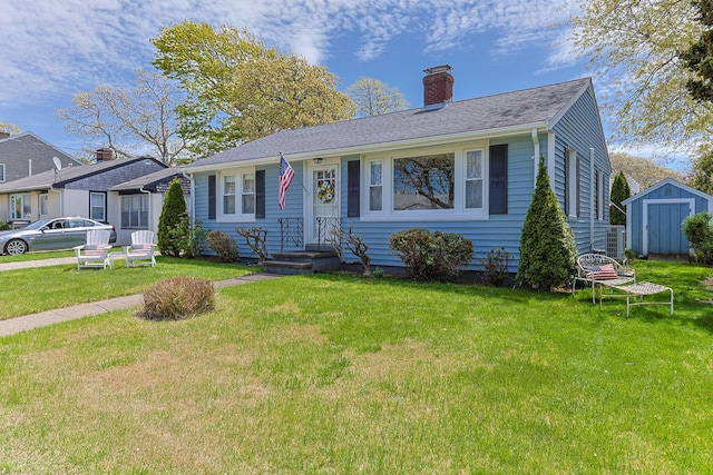view of front of house featuring a storage unit, a chimney, a front yard, and an outbuilding