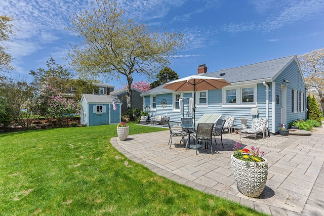 rear view of property with a patio area, a storage shed, a yard, a chimney, and an outdoor structure