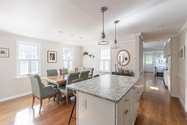 kitchen featuring a center island, light hardwood / wood-style flooring, hanging light fixtures, and ornamental molding