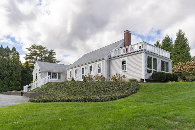 view of property exterior with a balcony and a lawn