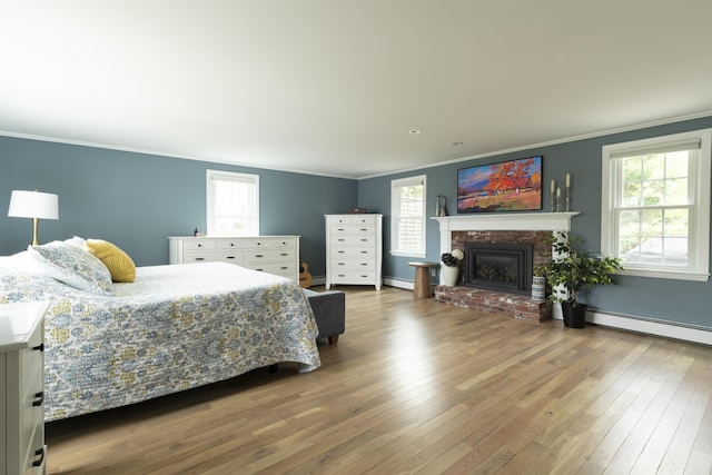 bedroom featuring a fireplace, hardwood / wood-style floors, multiple windows, and a baseboard heating unit