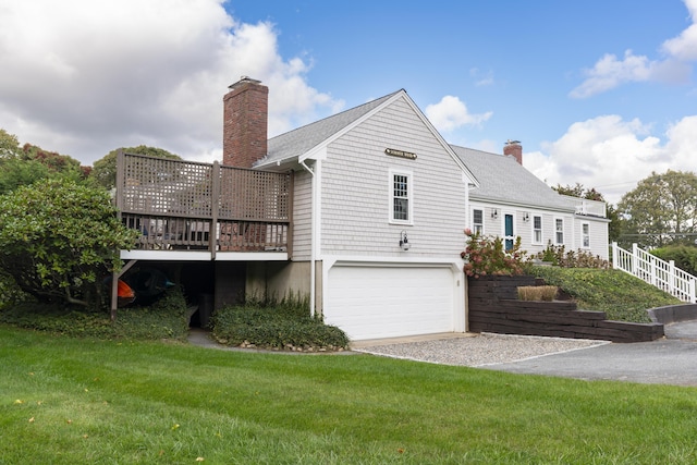 rear view of property featuring a garage, a wooden deck, and a lawn