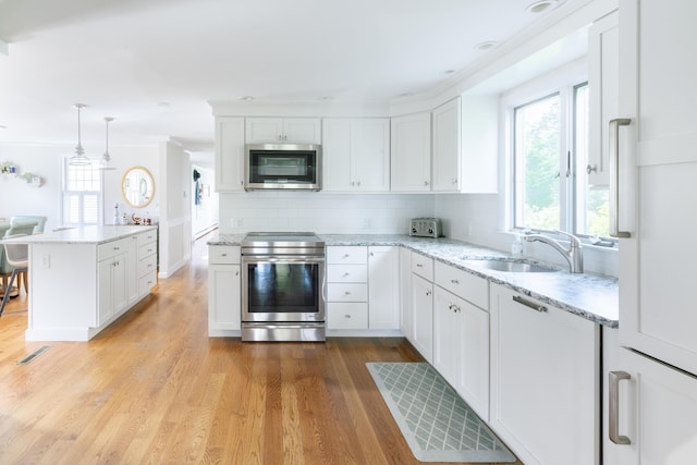 kitchen featuring sink, pendant lighting, white cabinetry, and stainless steel appliances