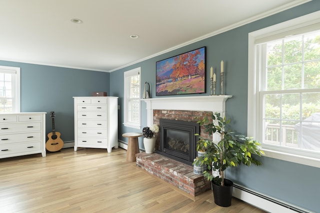 living area featuring a baseboard heating unit, light hardwood / wood-style floors, a fireplace, and crown molding