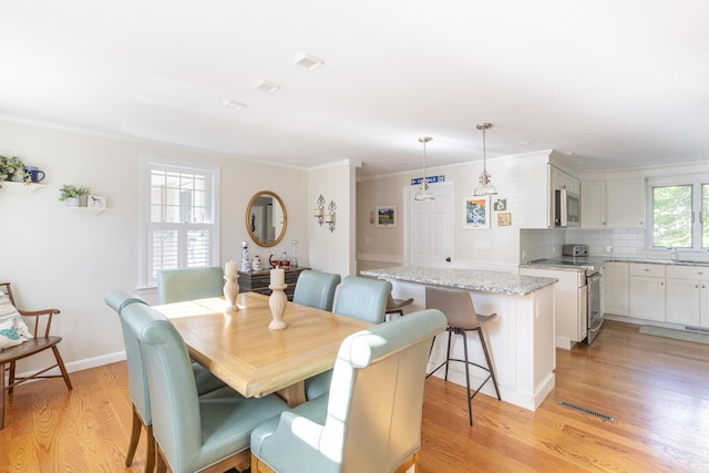 dining room featuring sink, crown molding, and light hardwood / wood-style floors