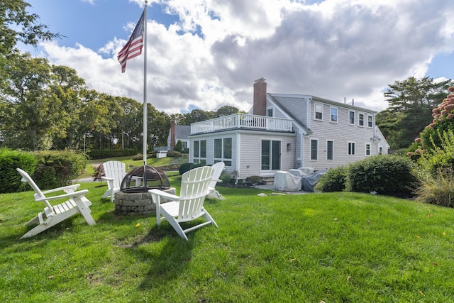 back of property featuring a fire pit, a lawn, and a balcony