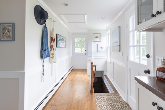 doorway to outside with baseboard heating, light hardwood / wood-style flooring, and ornamental molding