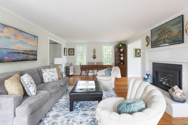 living room featuring hardwood / wood-style flooring, a brick fireplace, and crown molding