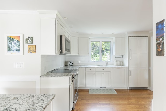 kitchen featuring white cabinets, appliances with stainless steel finishes, sink, backsplash, and light stone counters