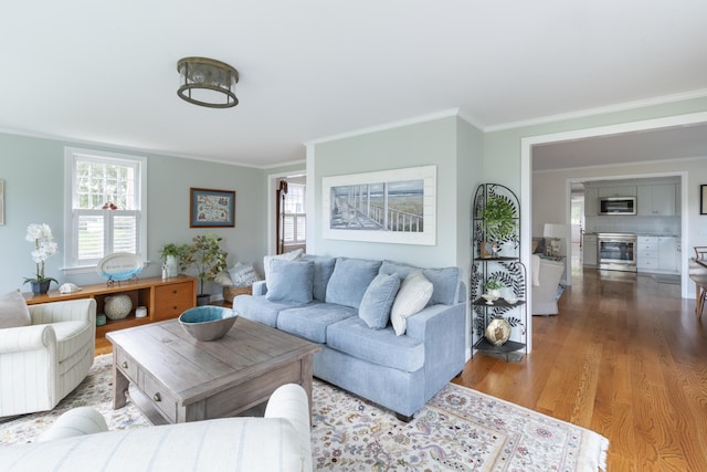 living room featuring a healthy amount of sunlight, ornamental molding, and hardwood / wood-style floors