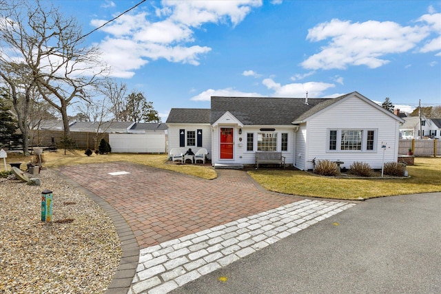 view of front of property featuring a front lawn, fence, and roof with shingles