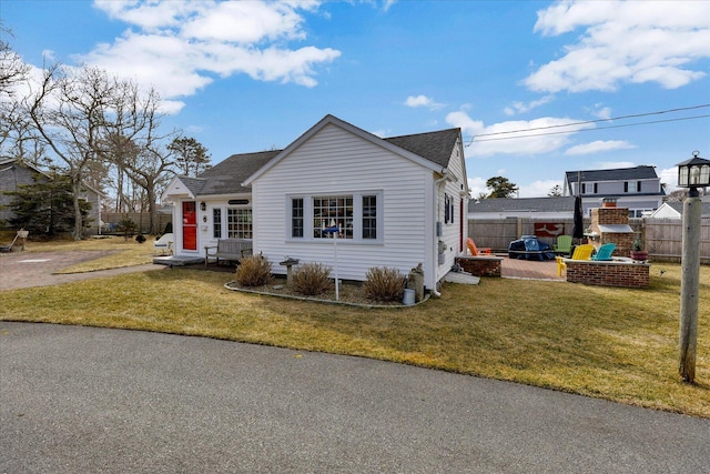 view of front of property featuring entry steps, a shingled roof, a front lawn, and fence