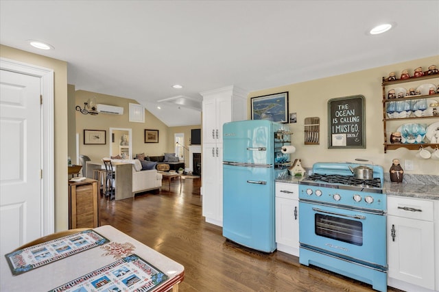 138 Sea St Unit 6, Dennis Port, MA 02639 - kitchen featuring stainless steel range with gas cooktop, freestanding refrigerator, a wall unit AC, white cabinetry, and lofted ceiling