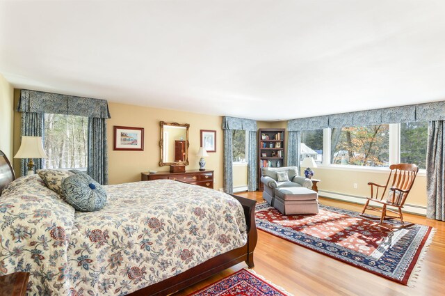 bedroom featuring baseboards, a baseboard heating unit, and wood finished floors