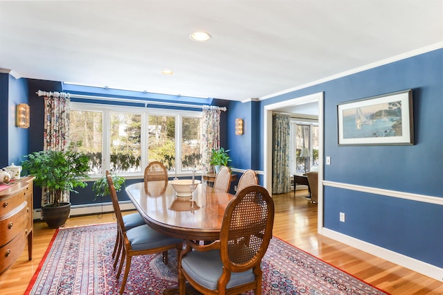 dining space with a baseboard heating unit, plenty of natural light, ornamental molding, and baseboards