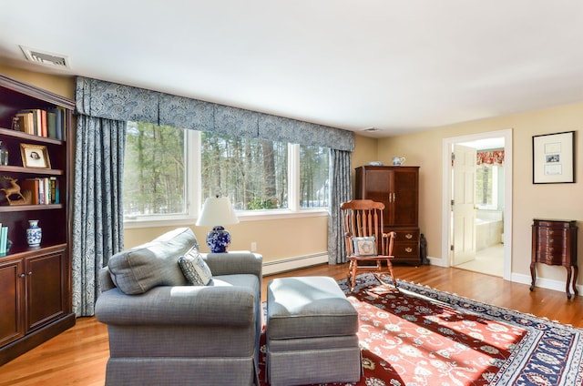 living area featuring baseboards, visible vents, light wood-style flooring, and baseboard heating