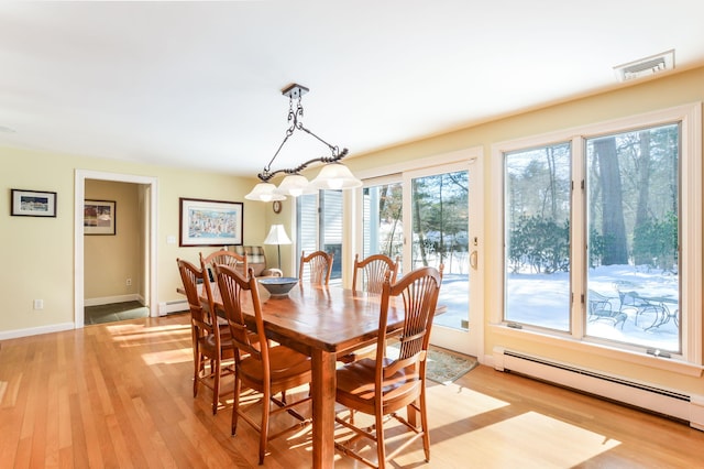 dining area with visible vents, light wood-style flooring, and baseboard heating