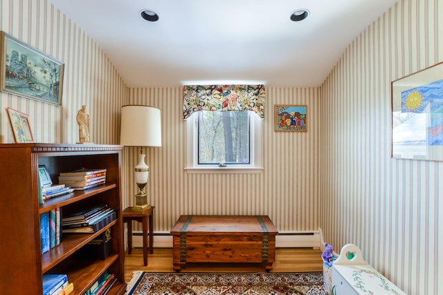 living area featuring wallpapered walls, a baseboard radiator, baseboard heating, and wood finished floors