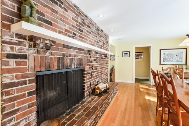 interior space featuring recessed lighting, brick wall, wood finished floors, baseboards, and a brick fireplace