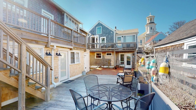exterior space featuring a wooden deck, outdoor dining space, and a balcony