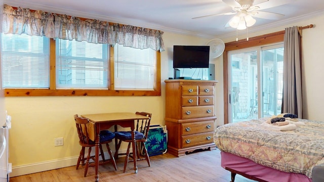 bedroom with crown molding, wood finished floors, multiple windows, and access to exterior