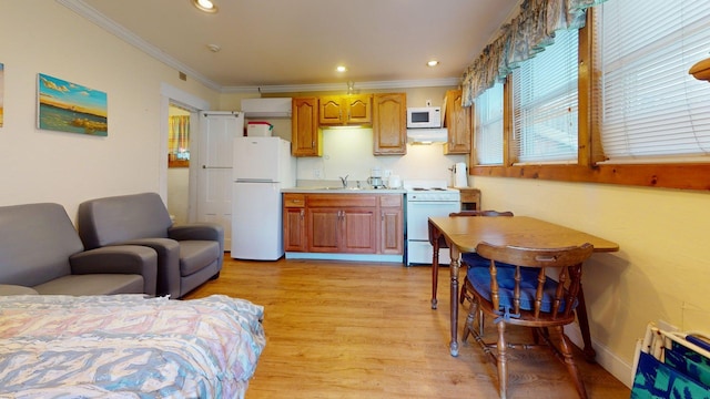 kitchen with crown molding, a sink, light wood-style floors, white appliances, and light countertops