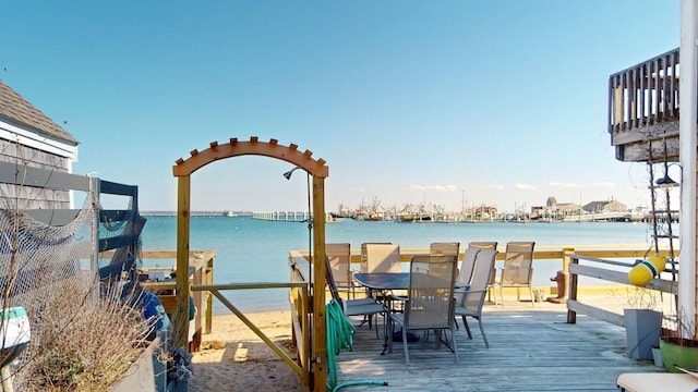 wooden deck with a water view and outdoor dining space
