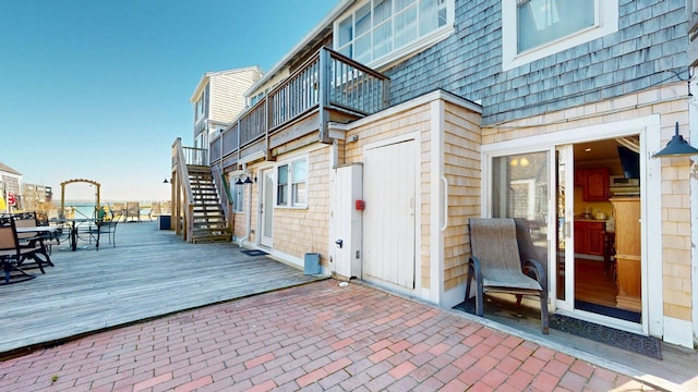 view of patio / terrace featuring a wooden deck, outdoor dining space, and stairs