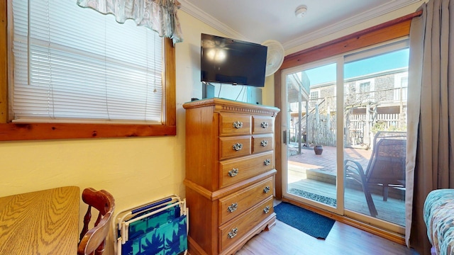 interior space with wood finished floors, crown molding, and access to outside