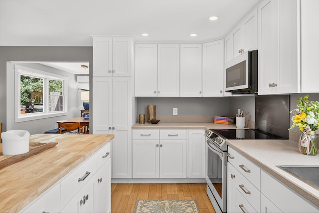 44 Squirrel, Eastham, MA 02642 - kitchen with stainless steel electric stove, light countertops, white microwave, light wood-style floors, and white cabinets