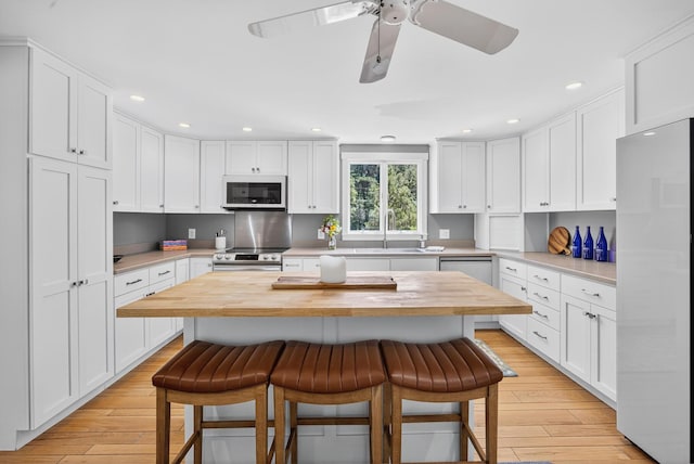 44 Squirrel, Eastham, MA 02642 - kitchen featuring wooden counters, a breakfast bar area, white appliances, white cabinets, and recessed lighting