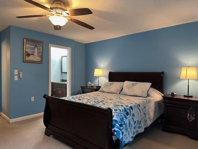 bedroom with baseboards, a ceiling fan, light carpet, and connected bathroom