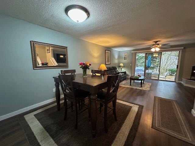 dining area featuring dark wood finished floors, baseboards, a ceiling fan, and a textured ceiling