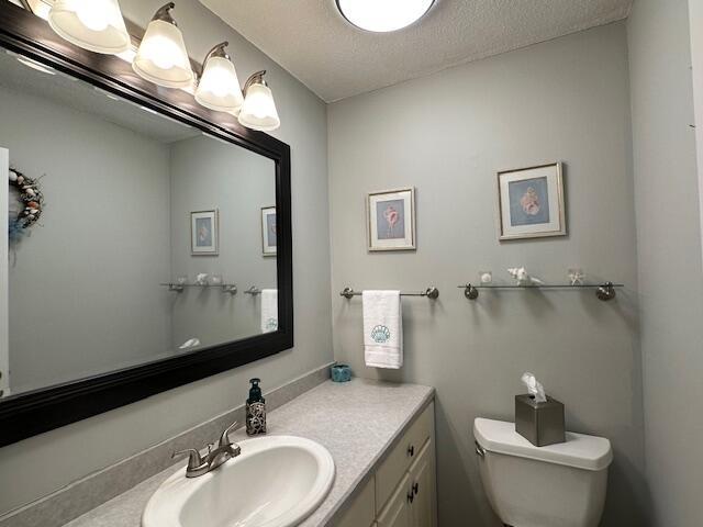 bathroom with toilet, vanity, and a textured ceiling