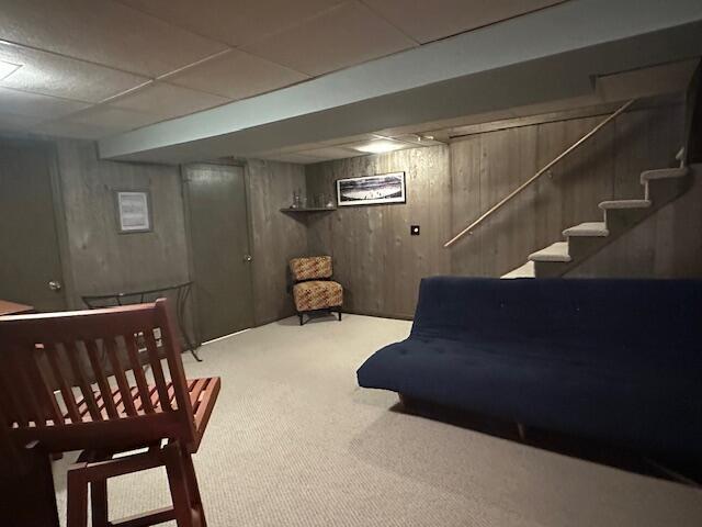 interior space featuring stairway, wooden walls, and carpet flooring