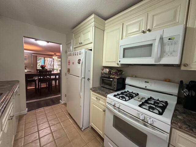 kitchen featuring light tile patterned floors, ceiling fan, white appliances, a toaster, and a textured ceiling
